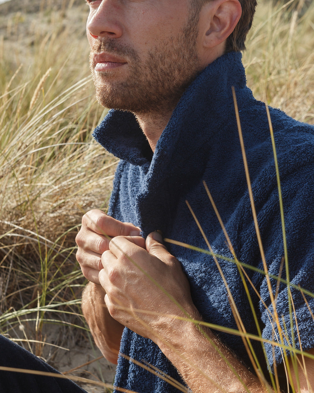 Navy Bond polo shirt by So English displayed on a hanger, close-up view showing the fabric and collar details.