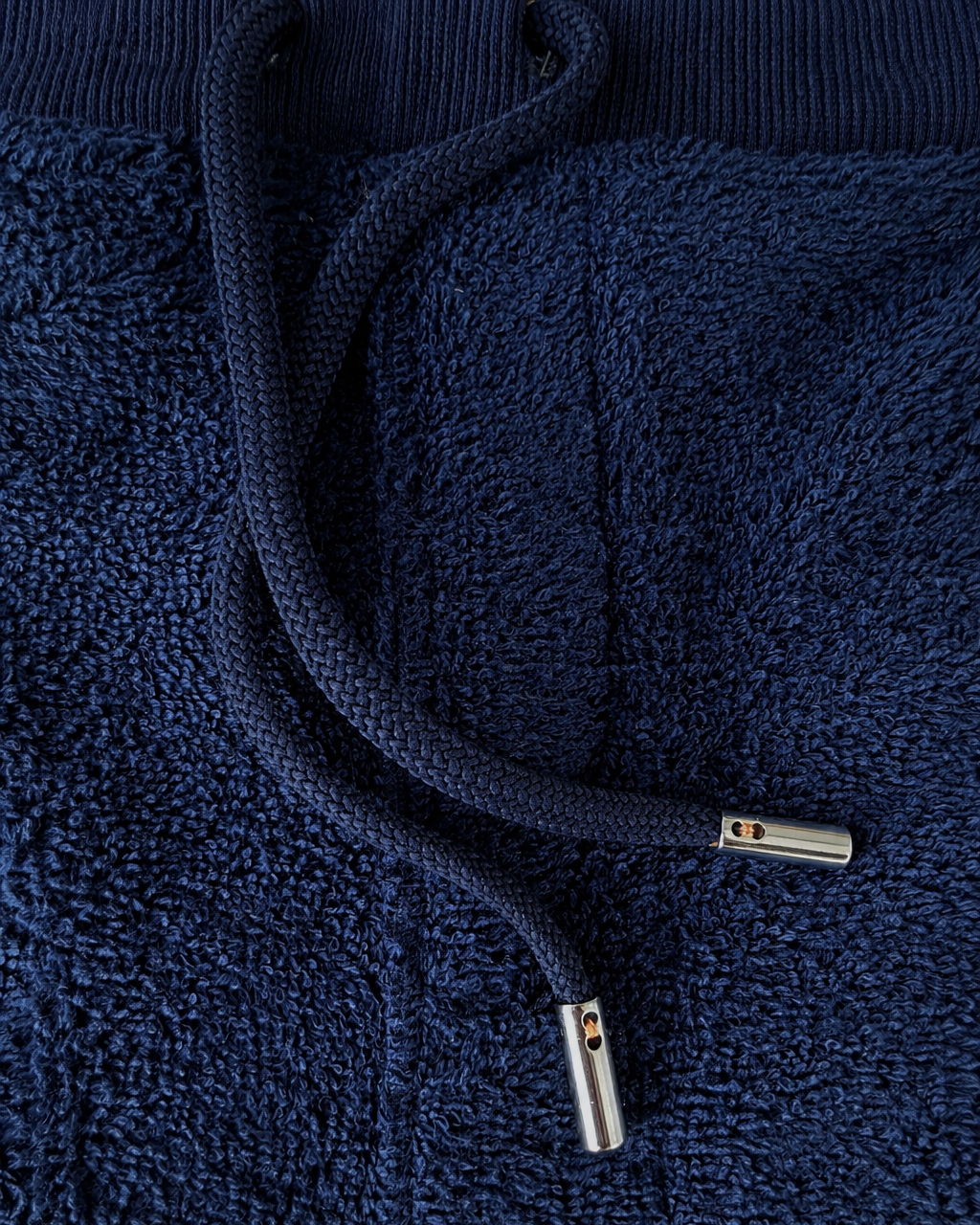 Close-up of navy blue terry cloth shorts by So English, showcasing the fabric texture and casual beachwear style.