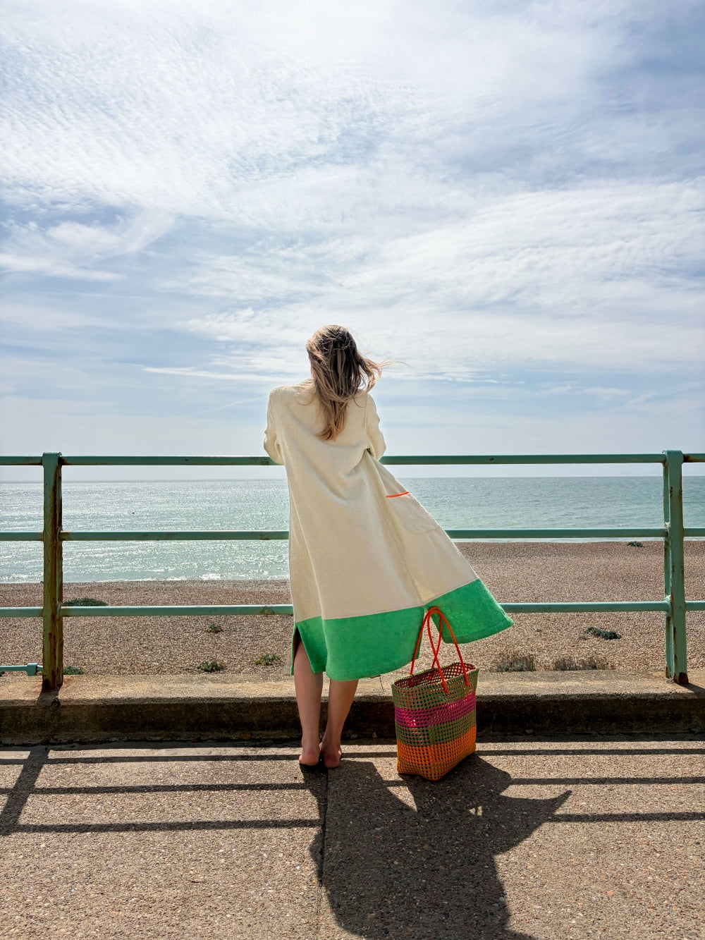 Model pictured from the back wearing Ramona almond + green long towelling robe at the beach
