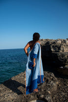 Model wearing Ramona blue long towelling robe with orange detail by the sea