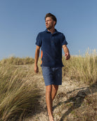 So English Bond polo shirt in navy and orange, featuring a casual fit and classic collar, worn by a model outdoors.