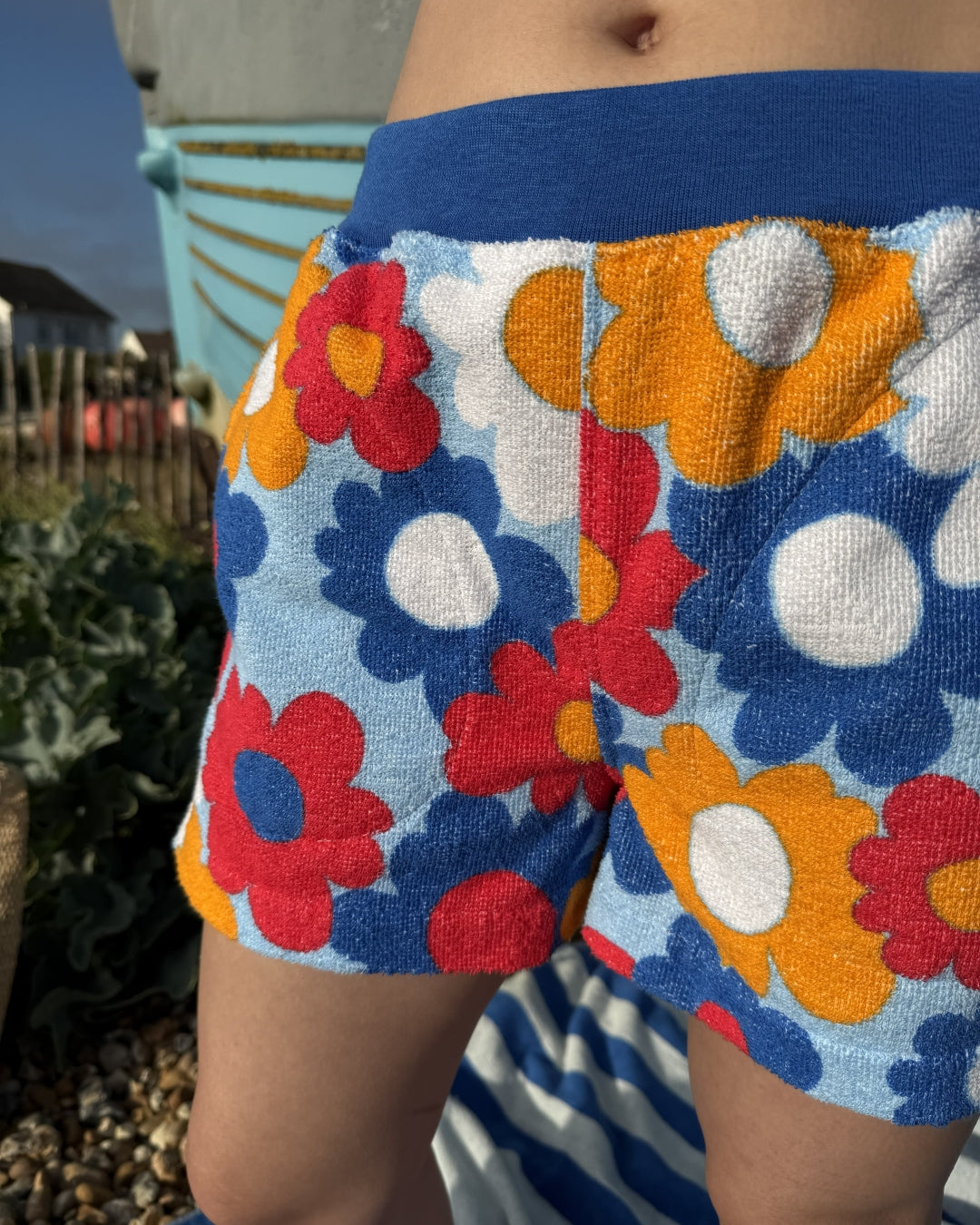 So English Carly print shorts featuring colorful beachwear design, made in the UK, displayed close-up on a model.