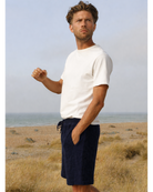 Man wearing navy Bear Shorts by So English on the beach, showcasing casual summer beachwear made in the UK.